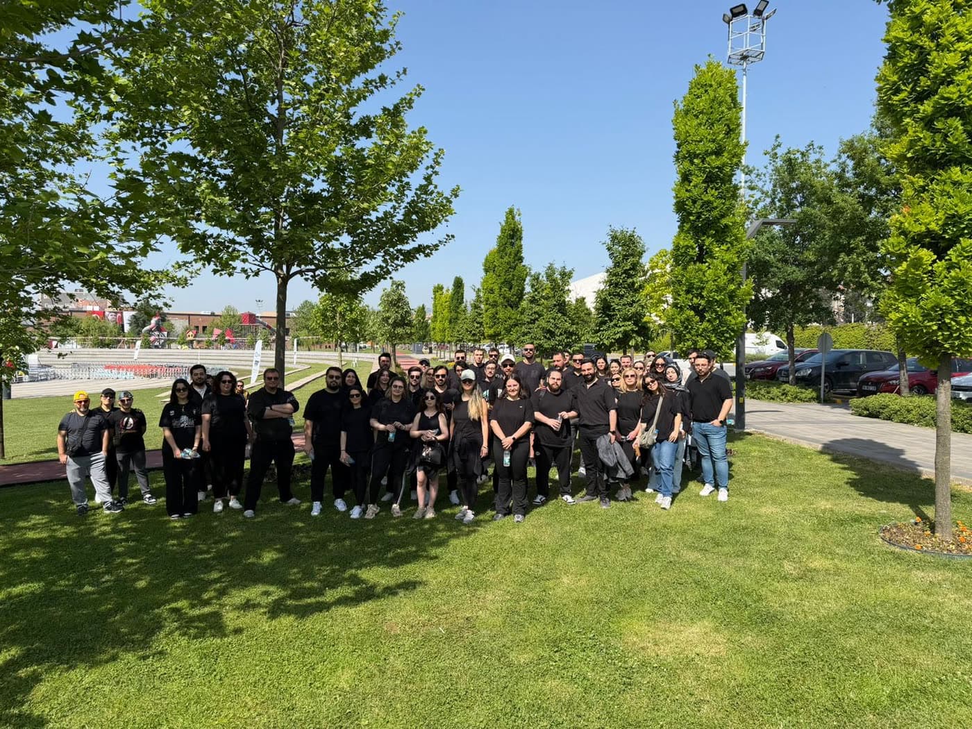 Ekip yeşil bir parkta toplu fotoğraf çektiriyor